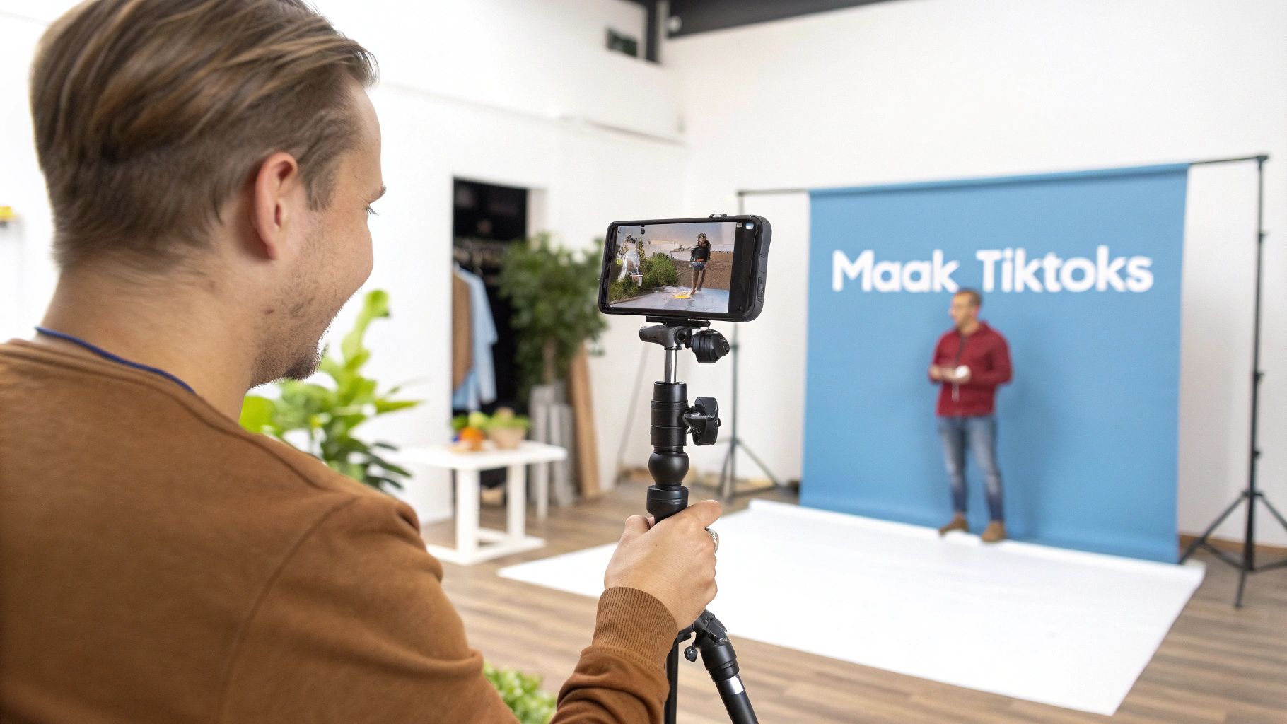 Een persoon filmt een ander persoon voor een blauw 'Maak Tik Toks' scherm met een smartphone op een statief.