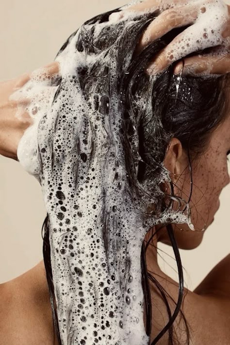 Maquilleuse appliquant un fond de teint sur une femme souriante au teint naturel