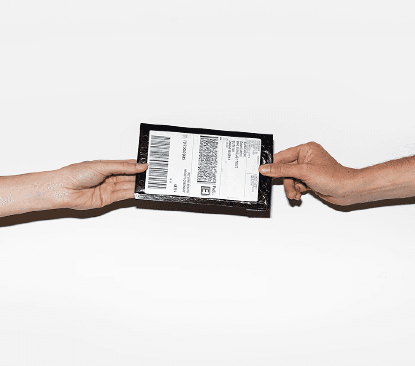 Hands passing a Rythm test kit package from one person to another.