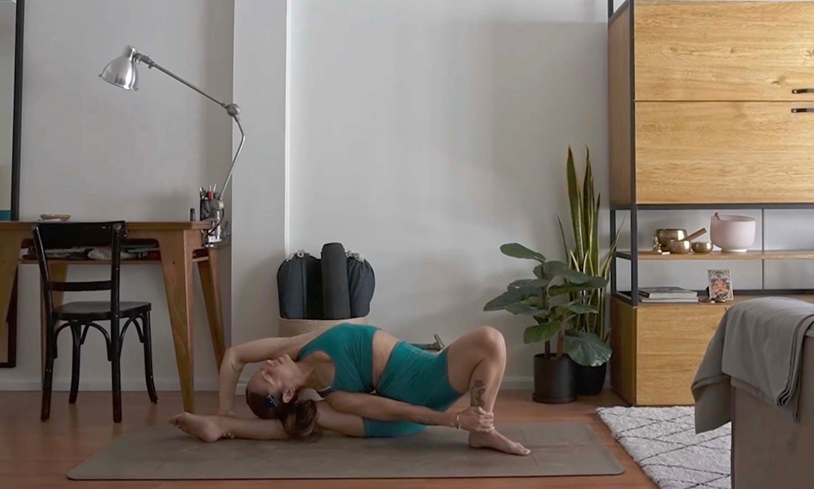 Flavia Siutti realizando una postura de torsión lateral recostada en una práctica de yoga.