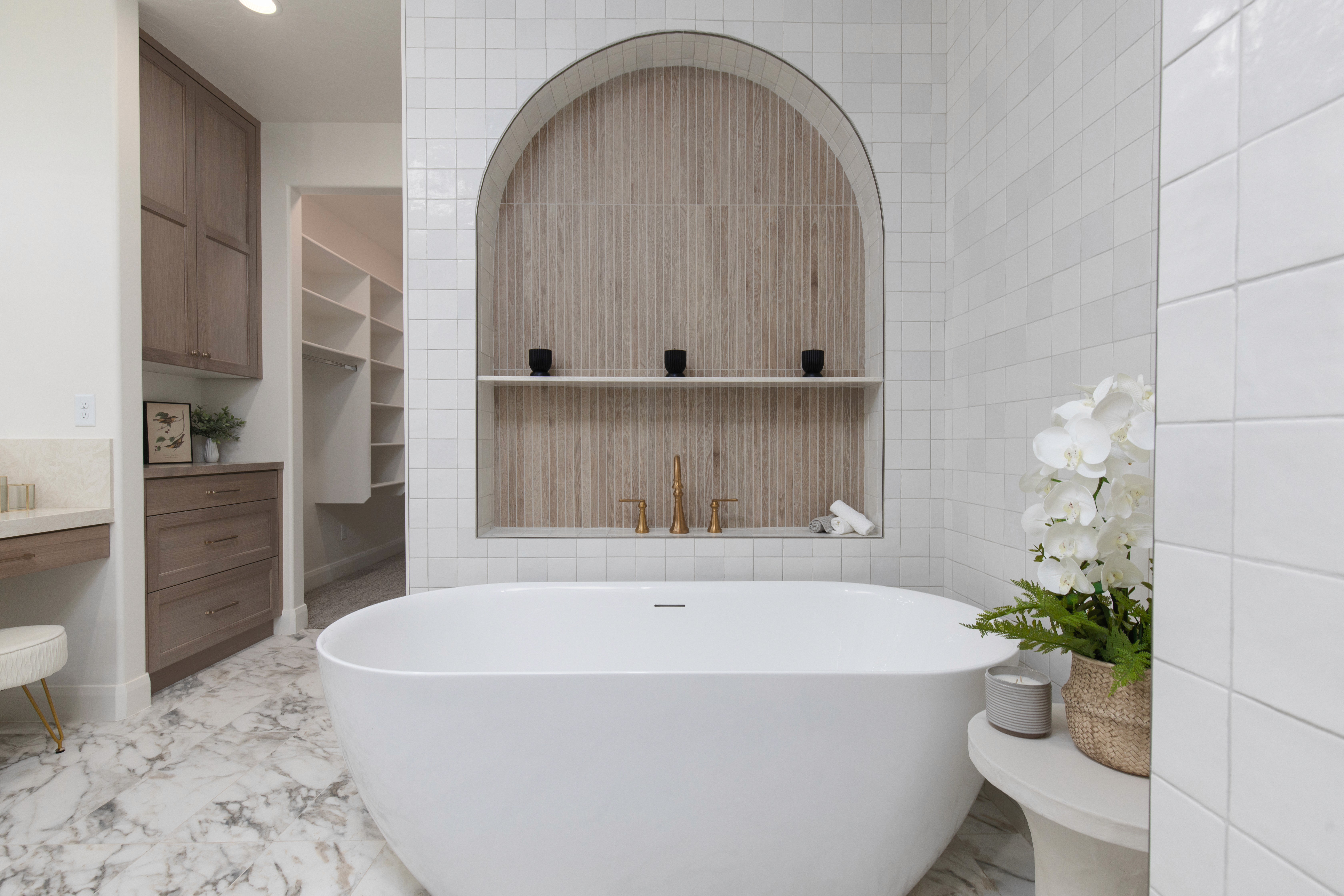 Southern Utah master bathroom with a freestanding tub, inset arched niche, and full tiled walls.