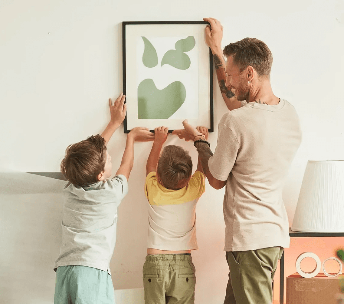 Family hanging up a picture frame.