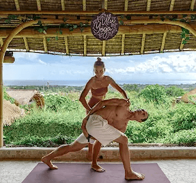 Instructor providing hands-on alignment adjustment to a student during yoga teacher training in the bamboo ocean-view shala.