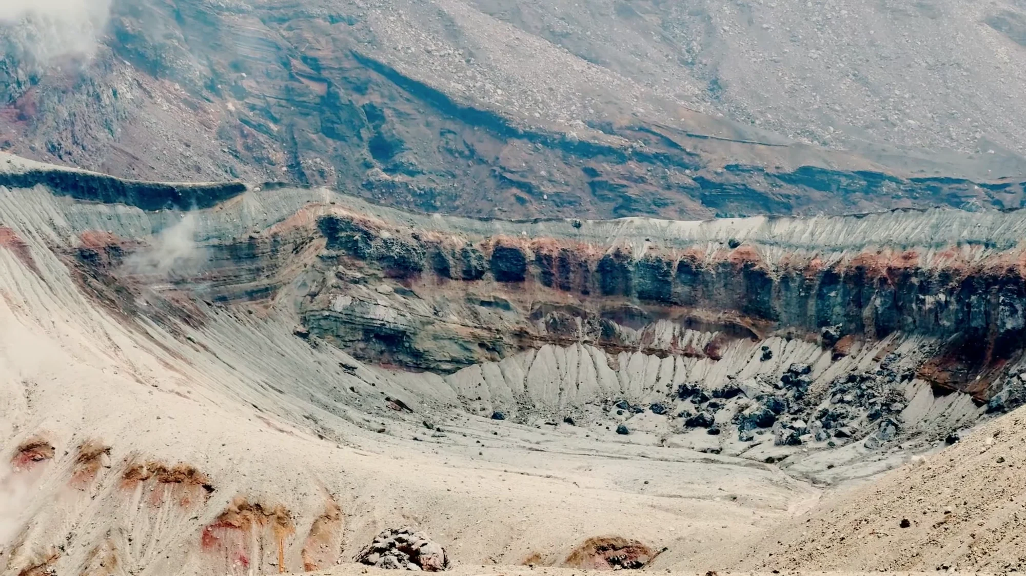 The banded rock wall and ash floor of a vast volcanic crater at Mount Aso