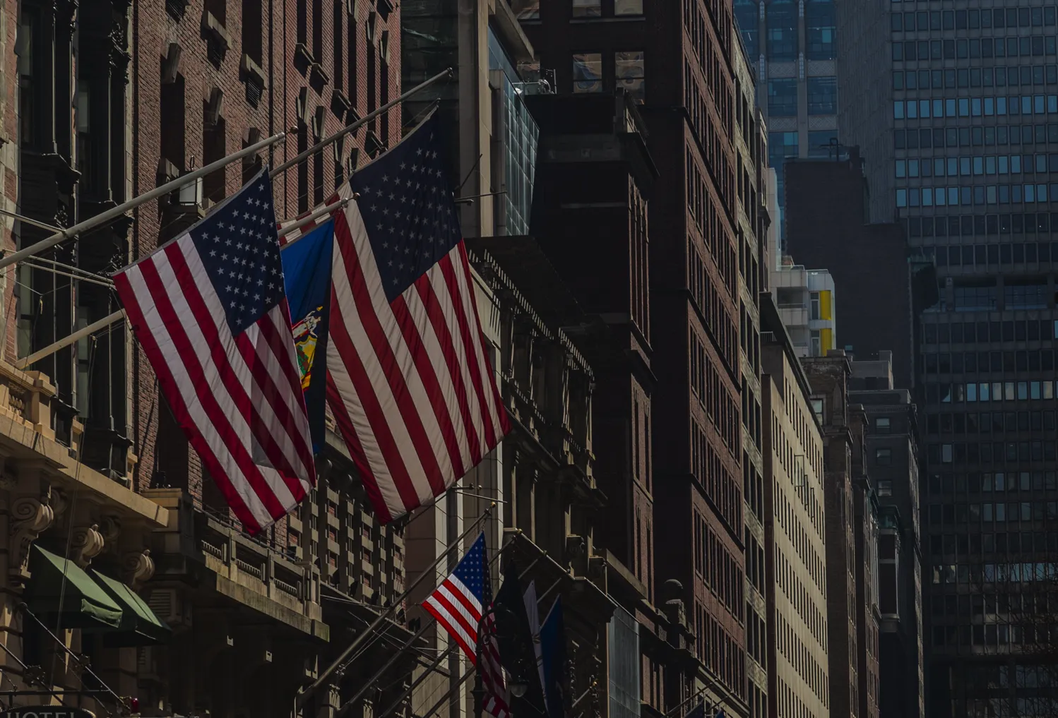 American flag hanging between historic and modern buildings on a New York City street.