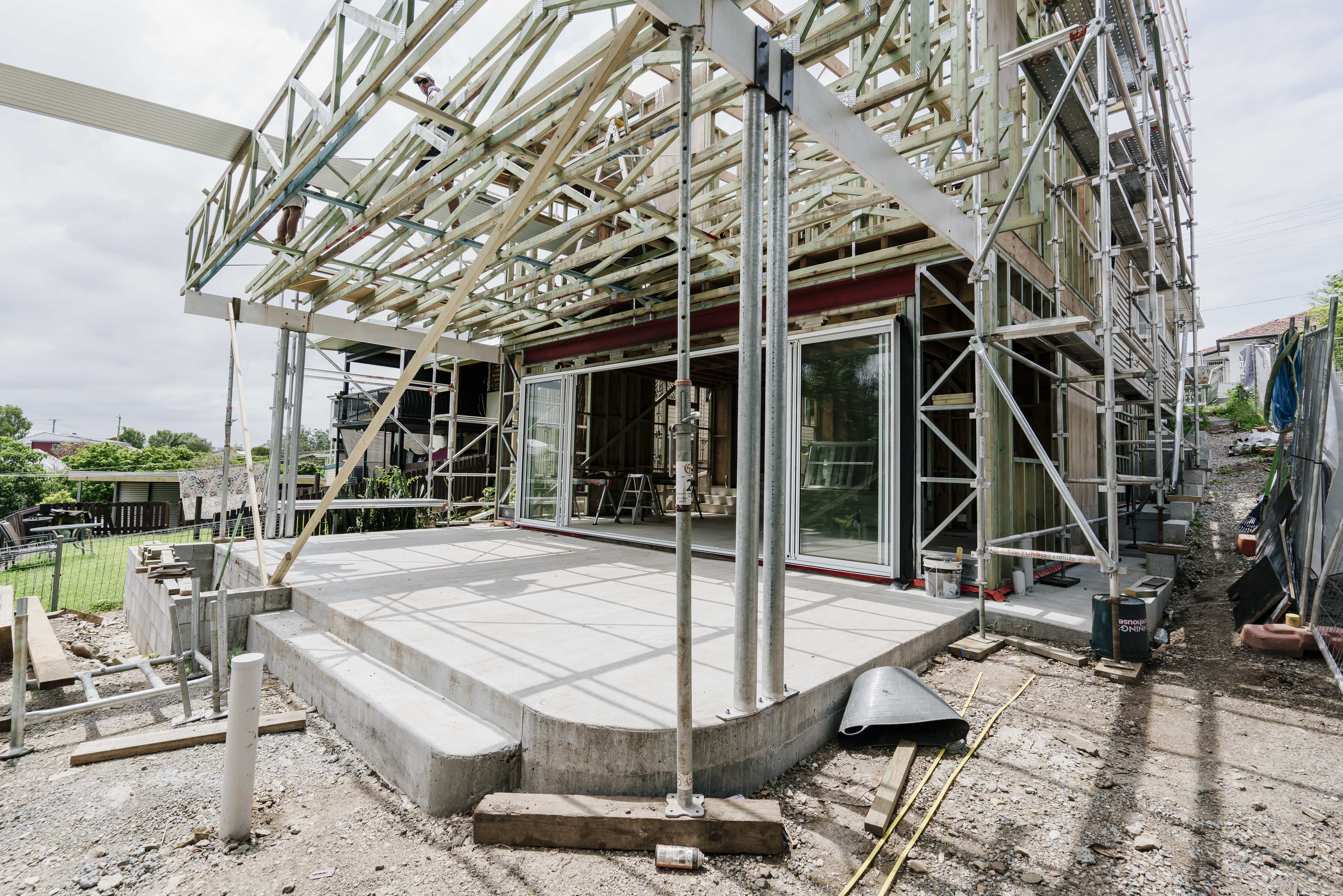 Rear home extension under construction in Balmoral, Brisbane, with the slab poured, steel posts and timber roof trusses up and sliding doors fitted, by Stark Builders