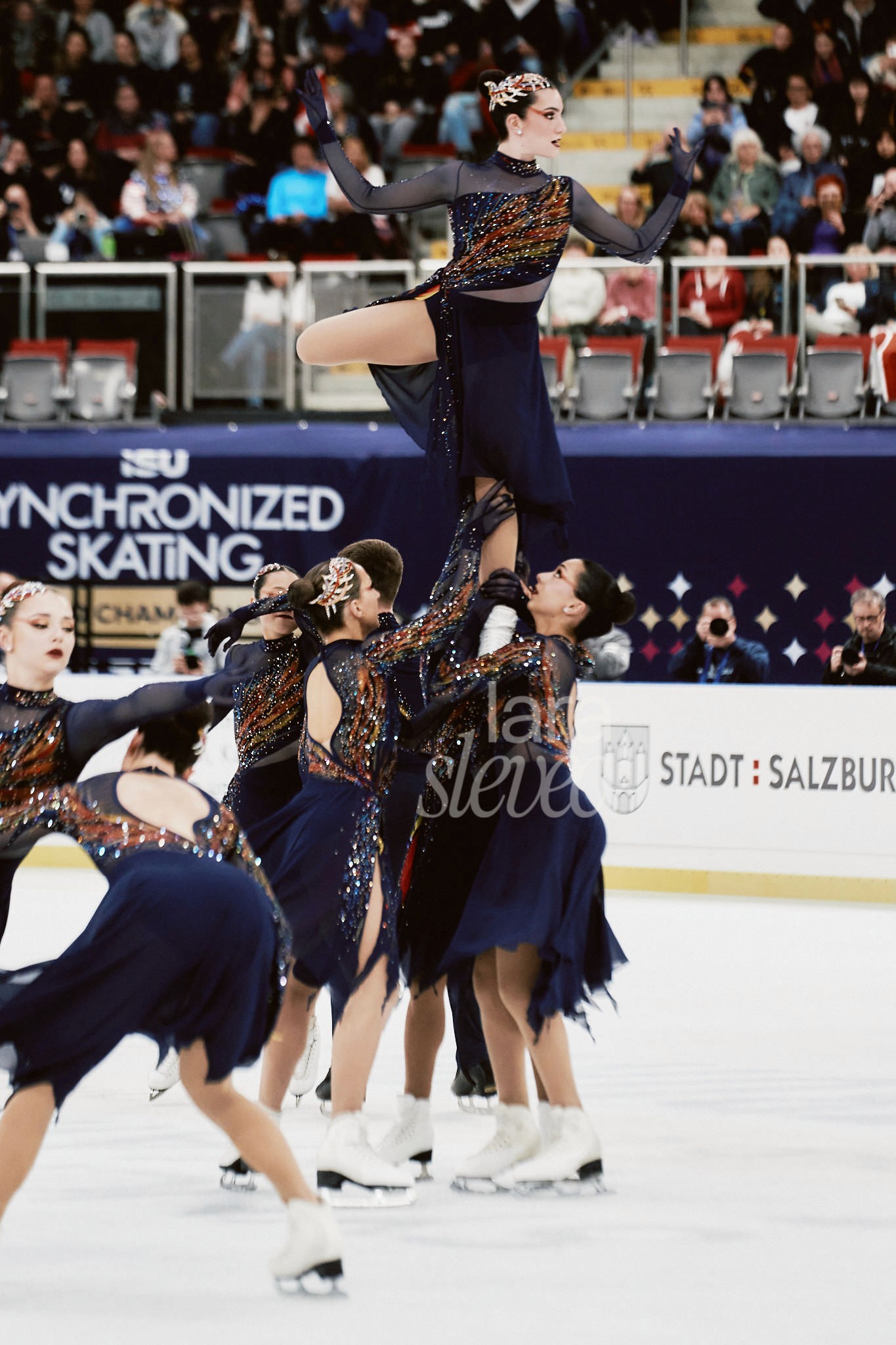 Hebung im Synchroneiskunstlauf zu der Musik Feuervogel. Team Les Supremes Kanada, die Sieger:innen des ISU Synchronized Skating Championships 2026 in Salzburg. Fotografiert von Lara Slevec.