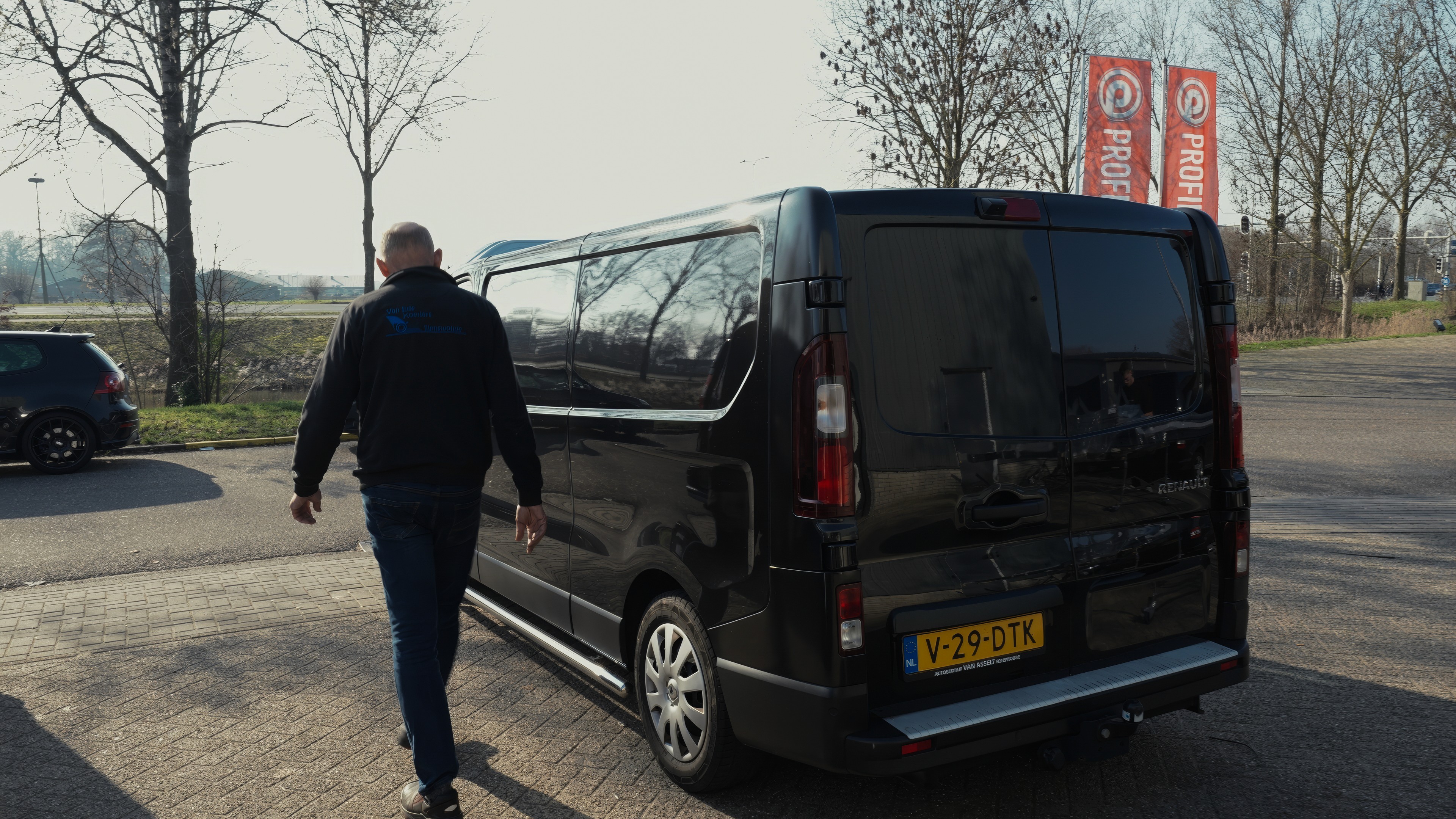 Zijaanzicht van een zwarte Van Ede Koeriers bestelbus geparkeerd voor een transportklus.