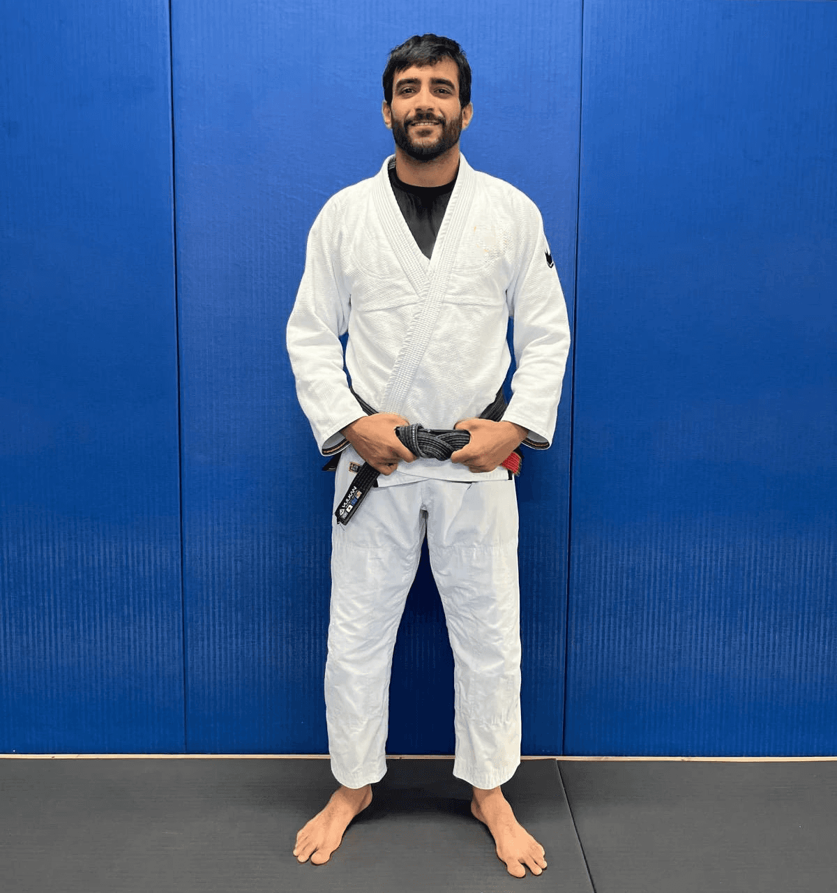 Maria Elisa Thimoteo smiling in her gi, hands folded in front of a gradient backdrop