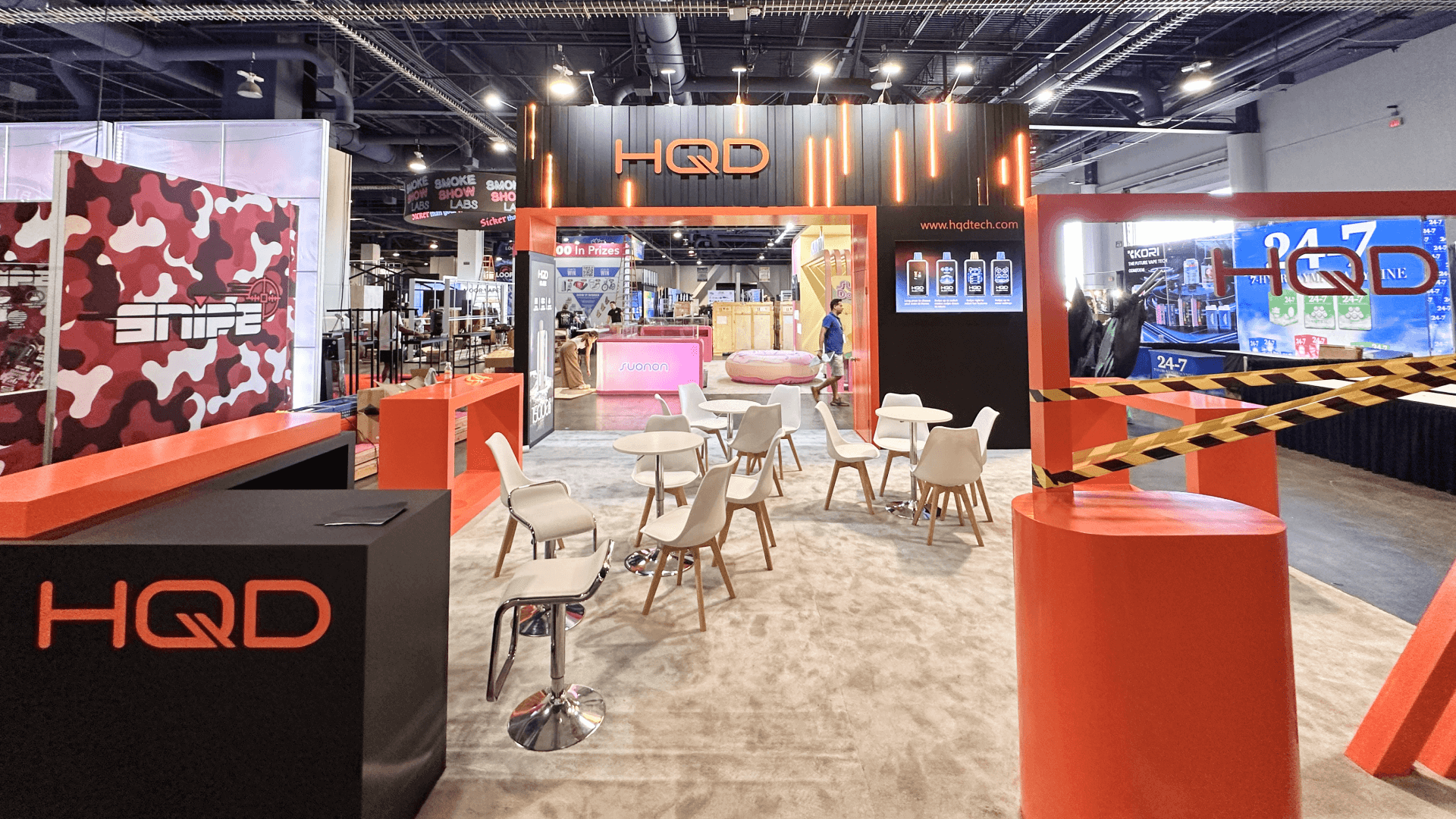 HQD CHAMPS Las Vegas 2025 20x20 retail product display booth with red branding, lounge seating, illuminated graphics, and open visitor flow