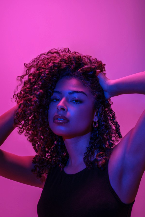 Curly-haired portrait with an arm raised under colored light