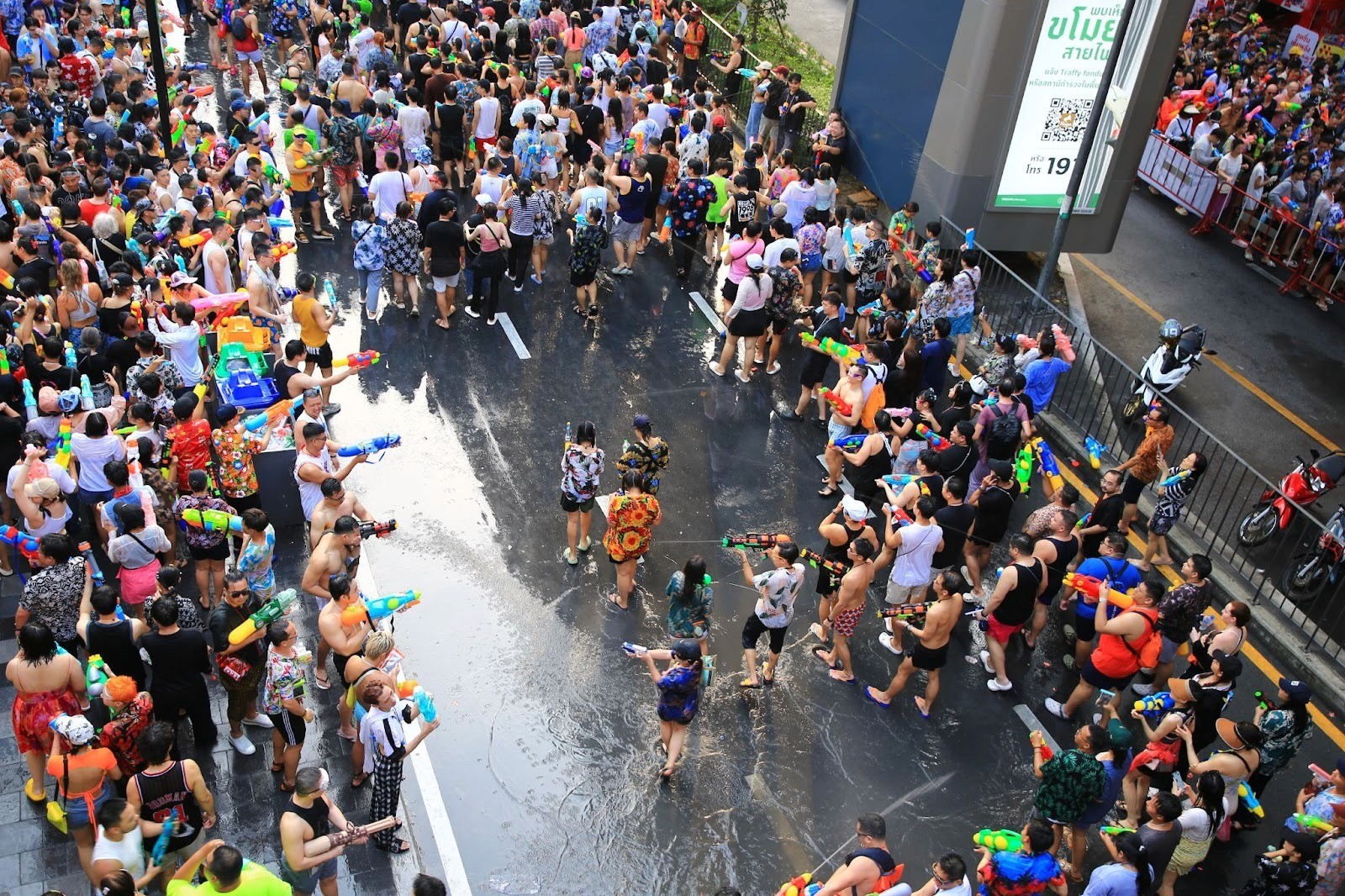 An aerial shot of wet crowds of people carrying water pistols and taking over a road in Thailand for the Songkran festival