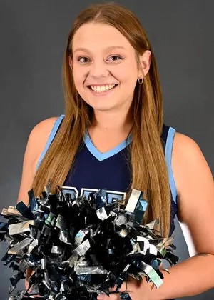 Emily Bierman, dressed in cheerleading team uniform, holds a pom pom and smiles for the camera