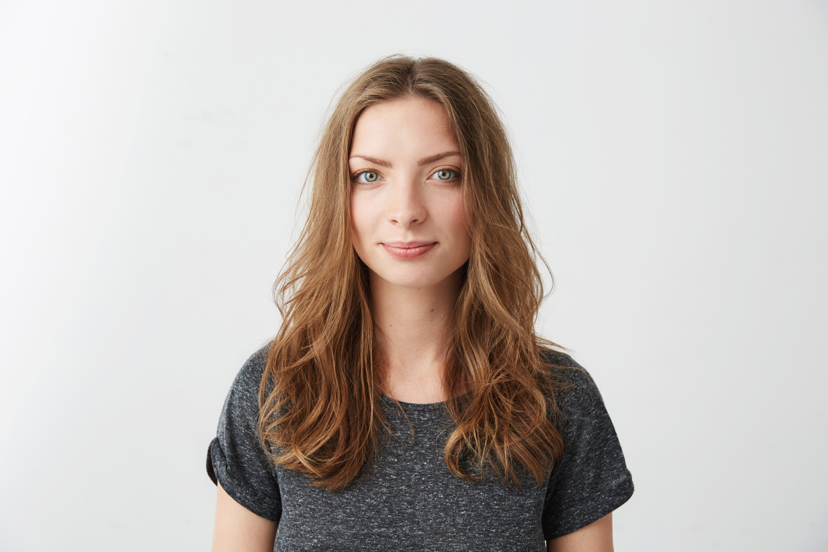 Portrait of a person with short dark hair wearing a green top and black jacket, looking directly at the camera against a neutral background.