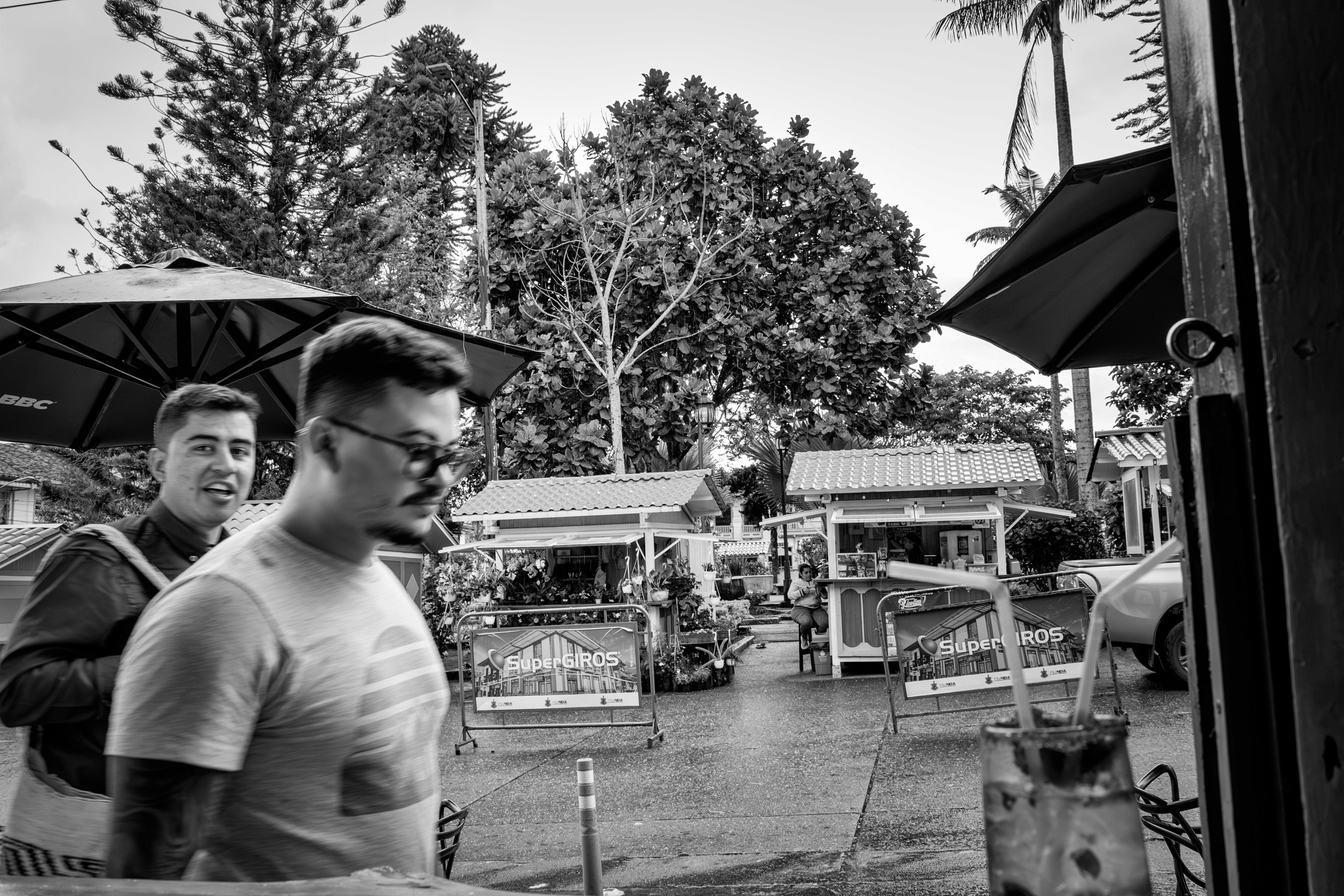 Rainy street scene with people passing by a bar window.