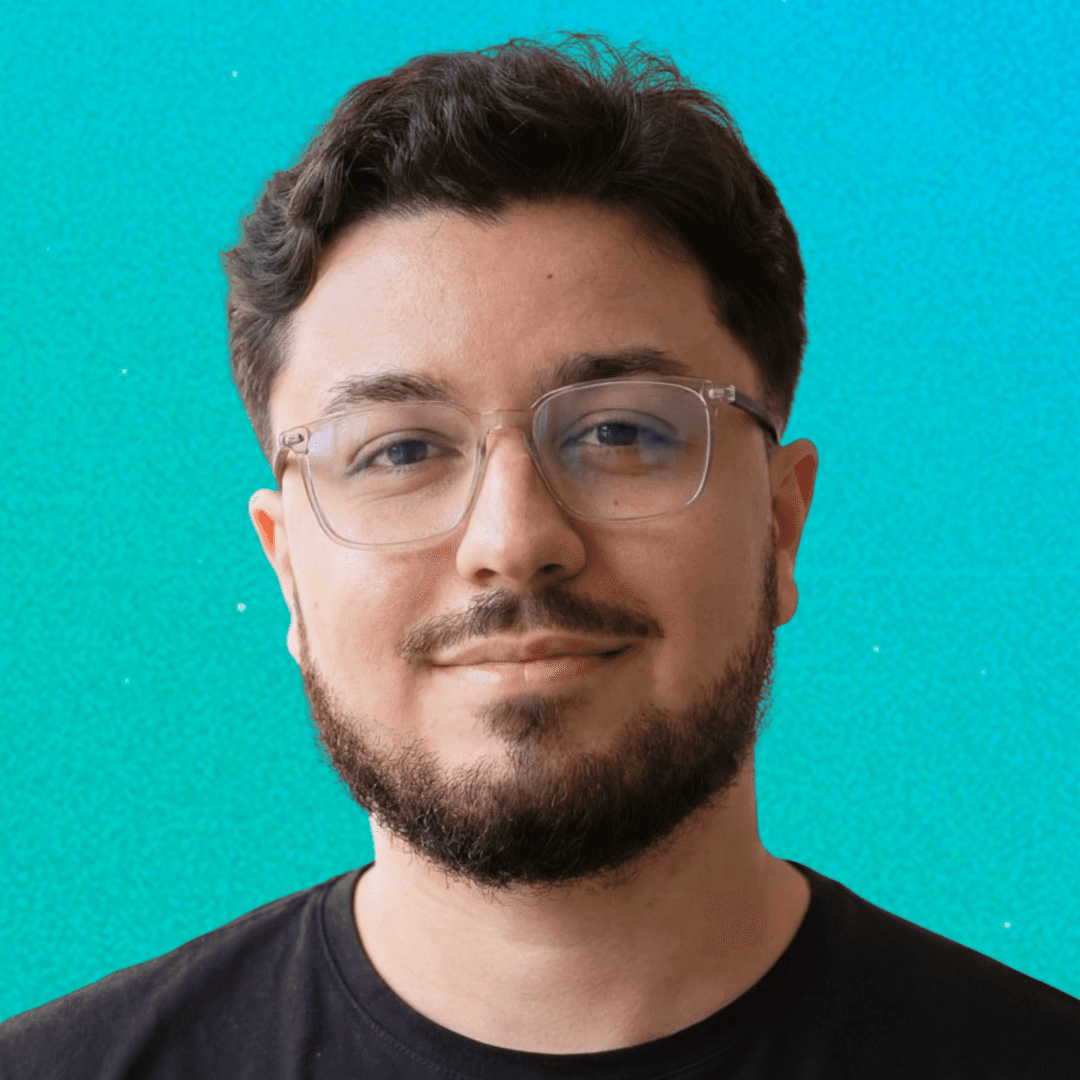 A person with wavy light hair stands facing slightly to the left, wearing a striped shirt against a neutral background.