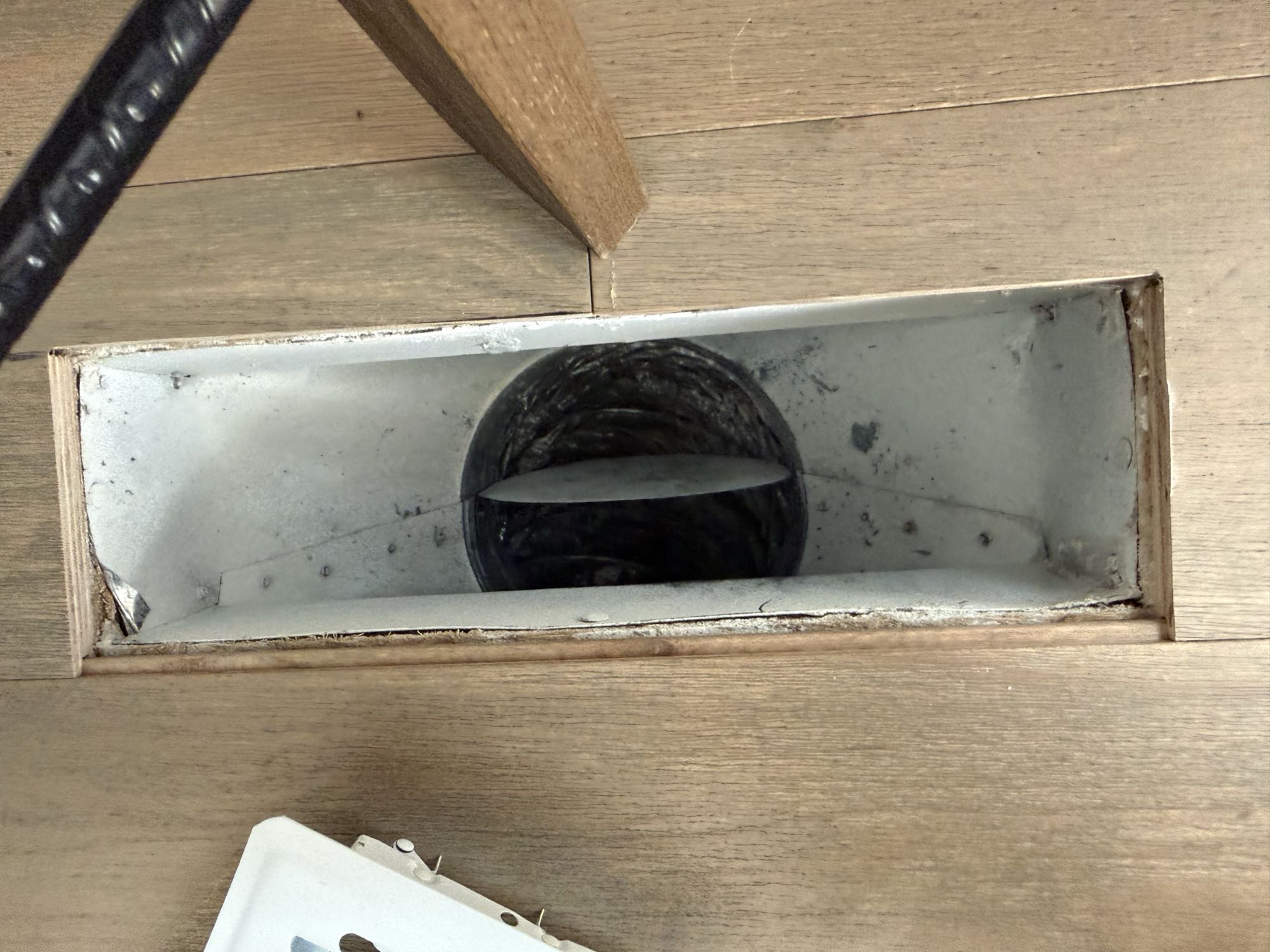 Open floor duct in a bedroom with the supply damper blade visible inside the boot.