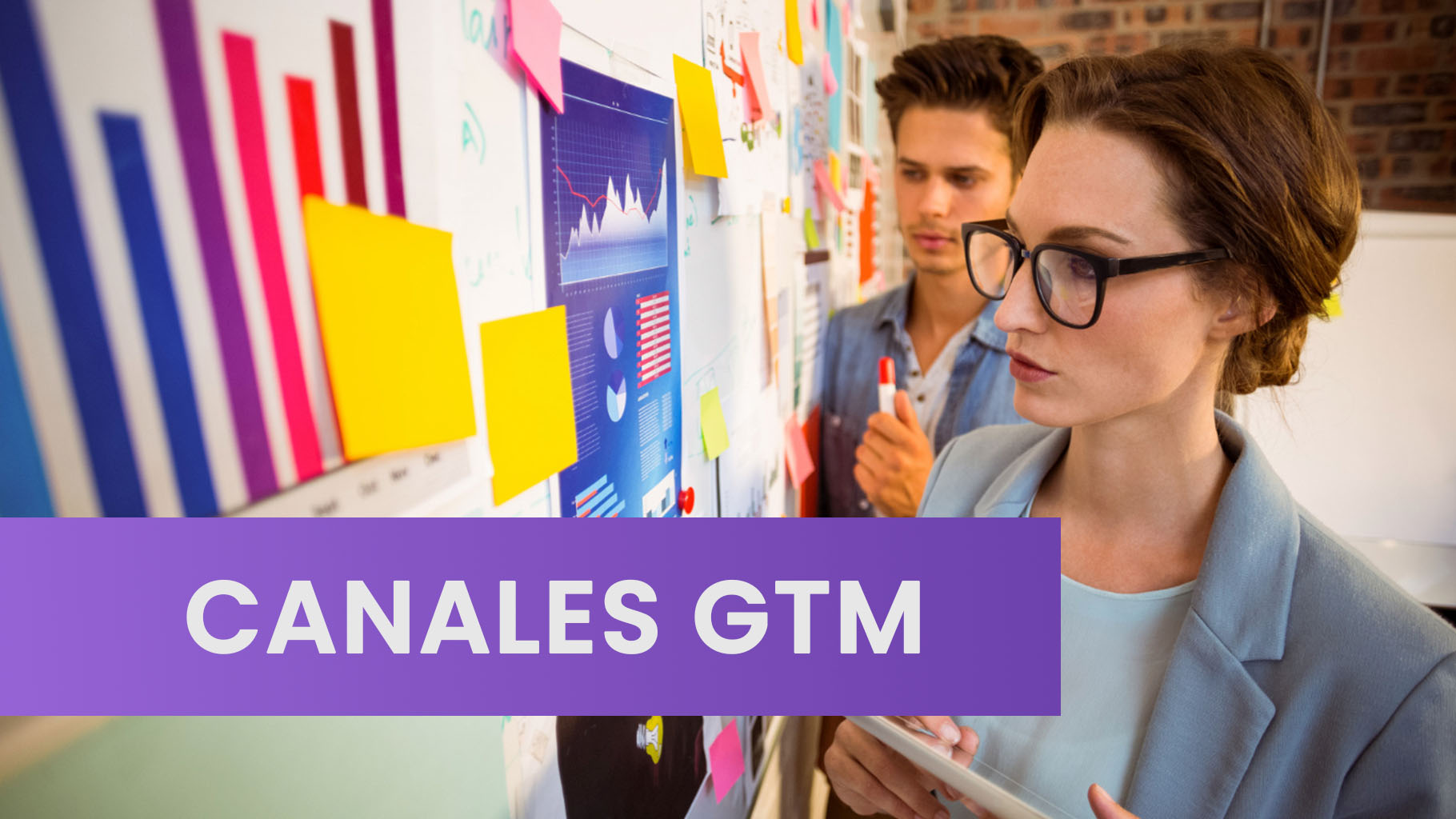 Personas de negocios colaborando en un espacio de trabajo moderno, analizando gráficos en una pantalla grande para planificar sus canales de venta y marketing.