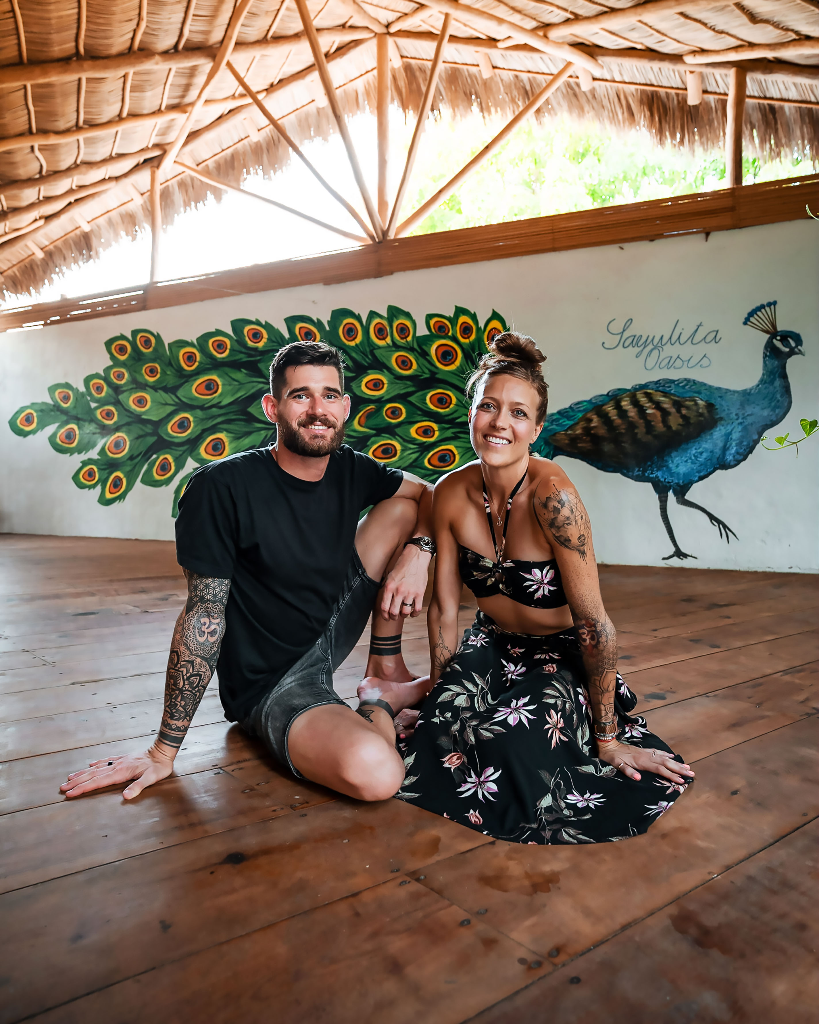 Bre and Flo sat beside eachother on a wood floor in a yoga studio