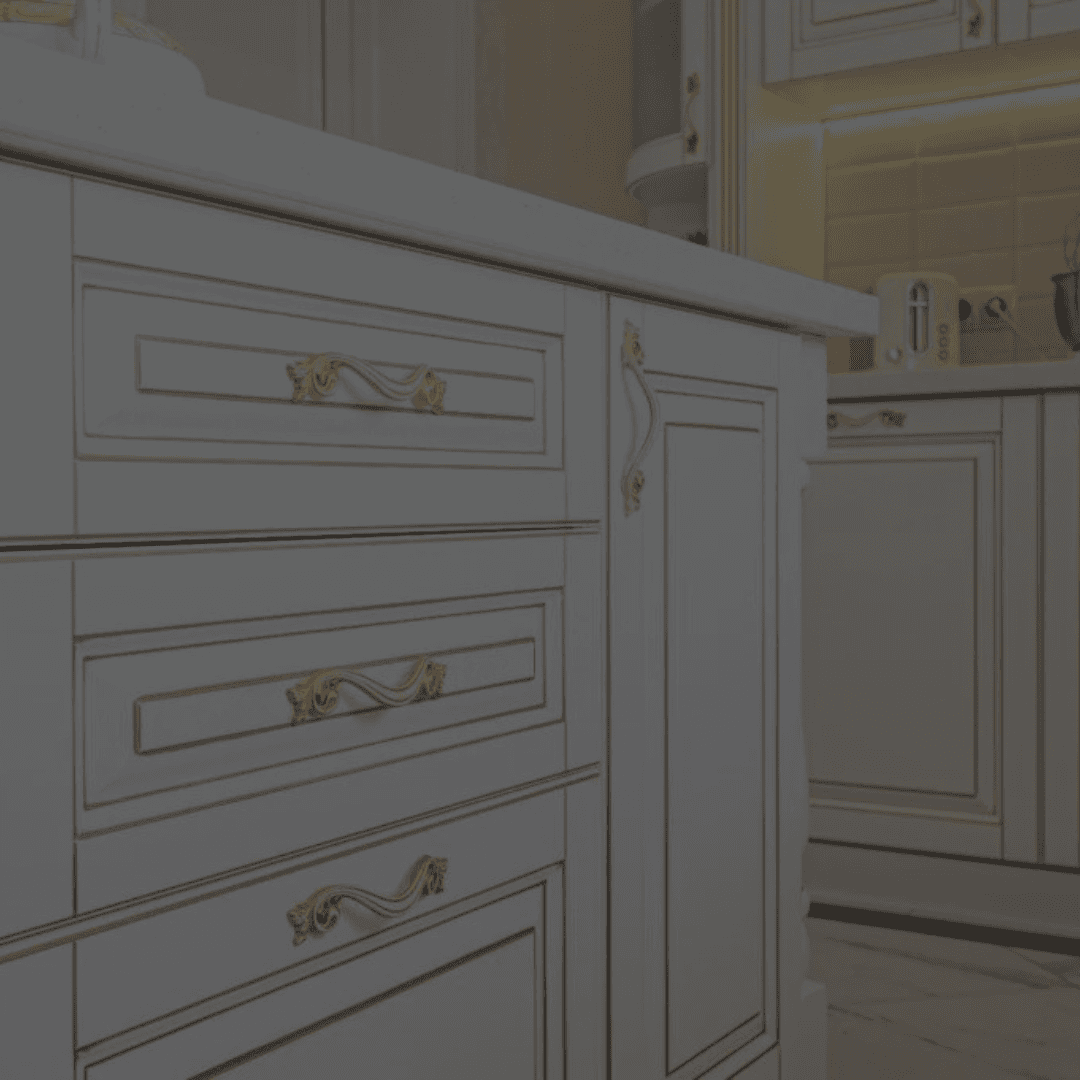 Close-up of a traditional-style kitchen cabinet with ornate gold handles and decorative trim, showcasing elegant detailing and a luxurious finish