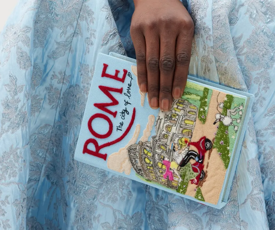 Image of a book called "Rome" being held by a person with a blue dress