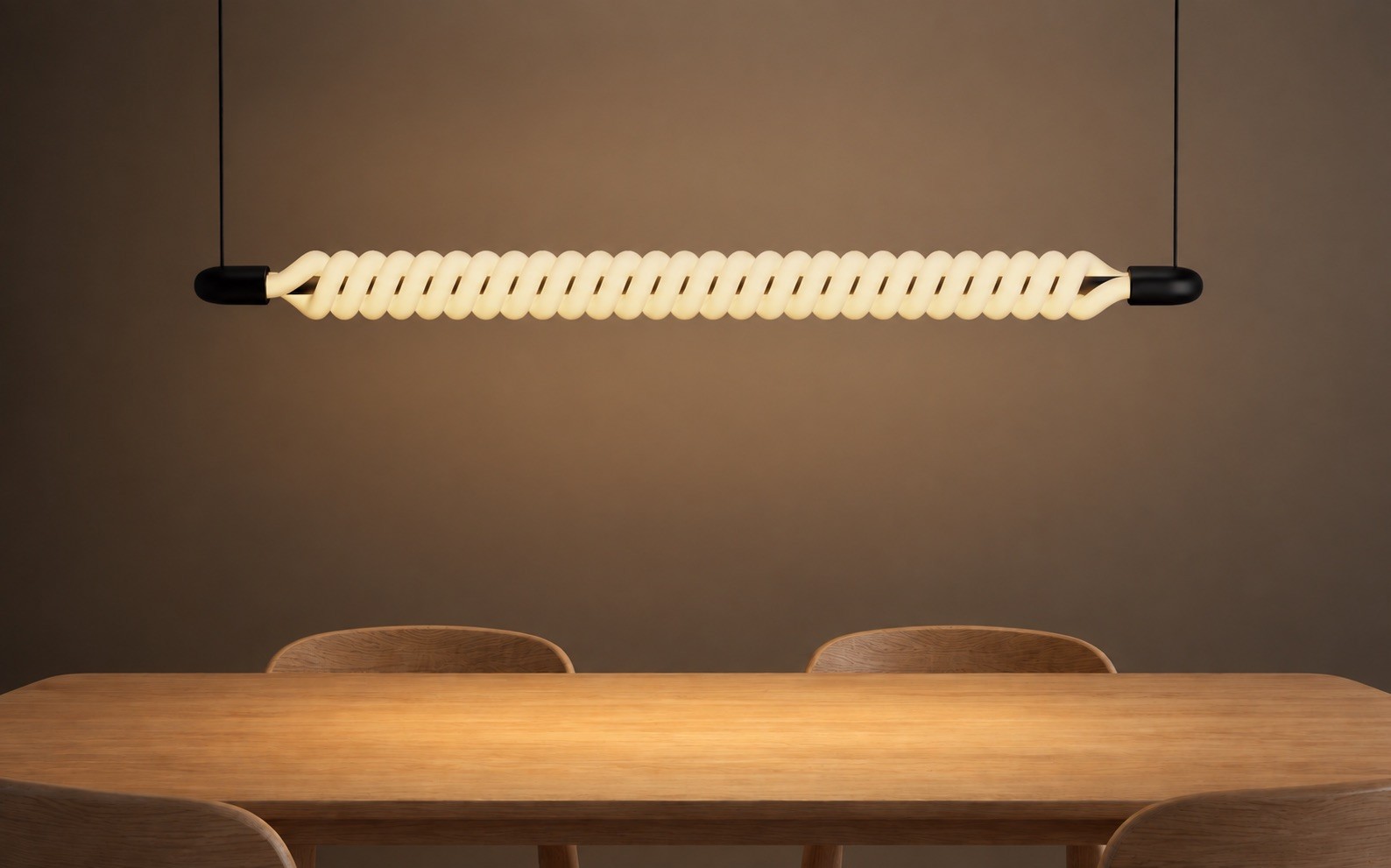 A long horizontal pendant light made of two glowing tubes wound around each other, hanging above an oak dining table.