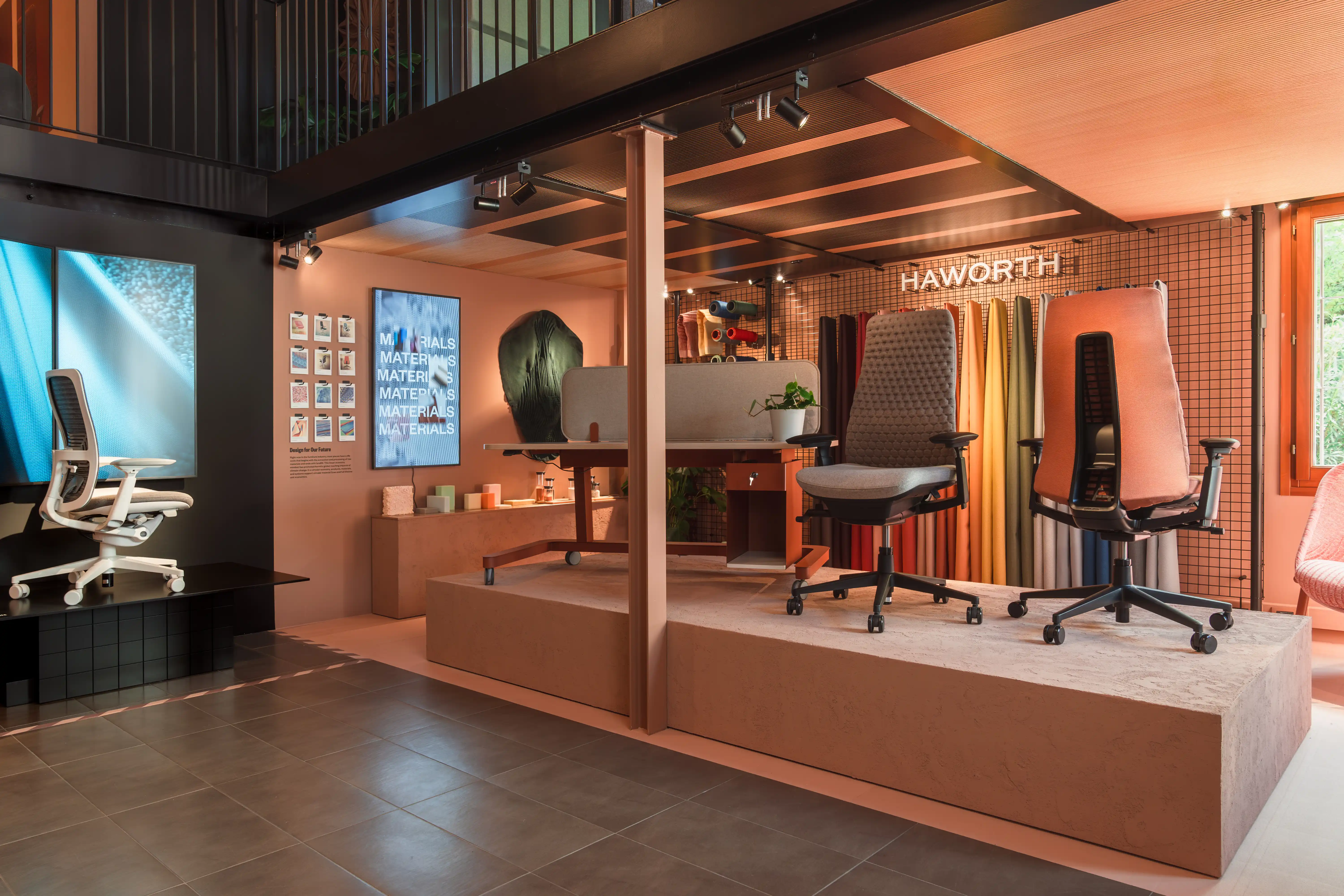 Terracotta-toned Haworth showroom with office chairs on podiums in front of the colorful fabric wall.
