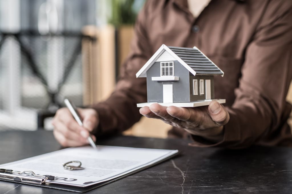 Preventive maintenance schedule illustrated by a person signing property documents while holding a model house.