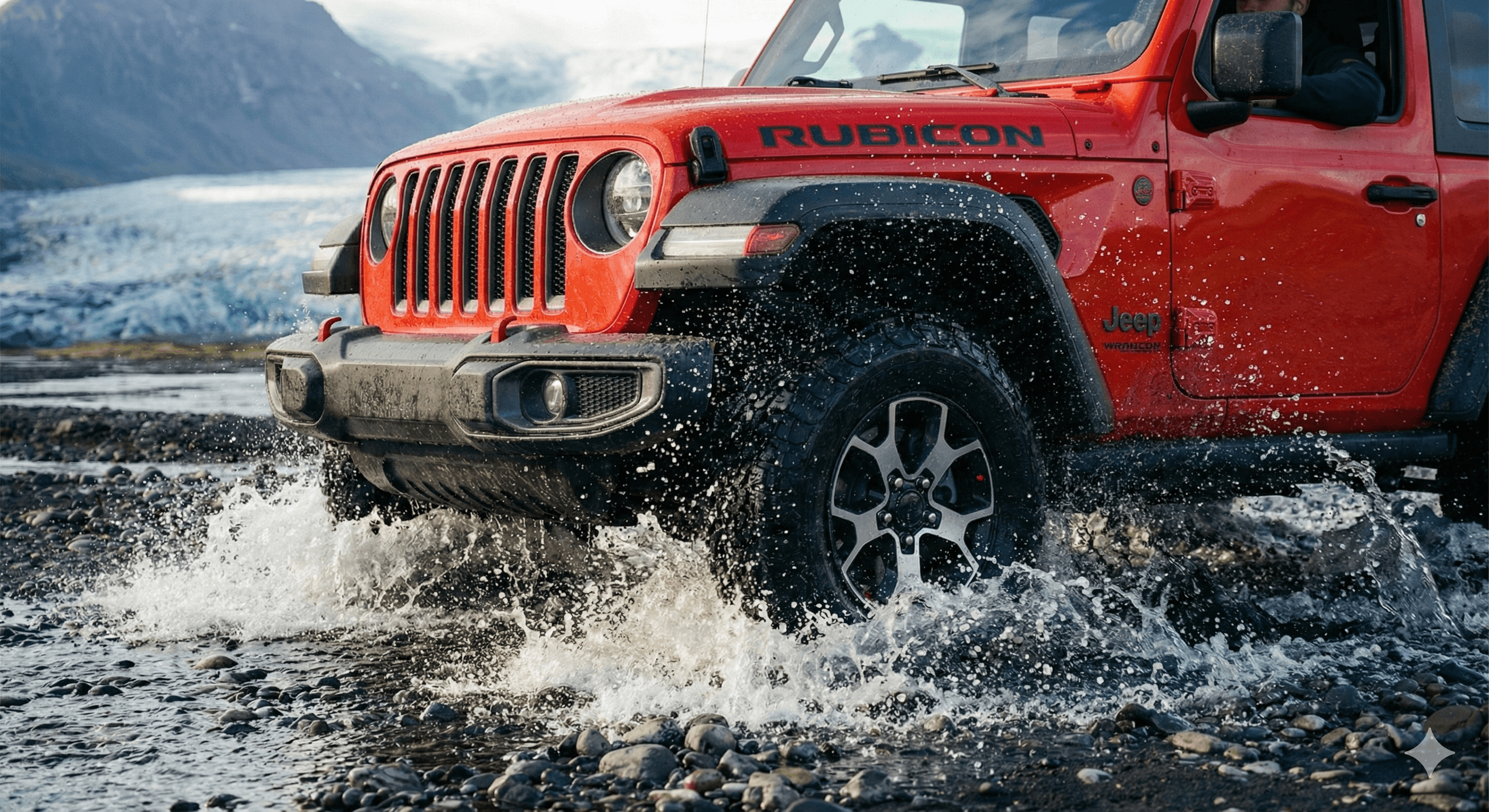 Close-up of a red Jeep Wrangler driving through water, creating a splash.