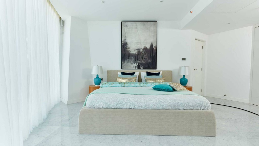 A spacious bedroom at The Pad by OMNIYAT featuring white walls and a large, inviting bed.
