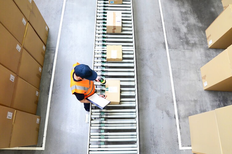 Worker scanning packages on a conveyor belt in a warehouse