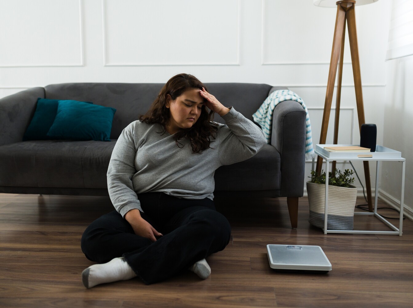 woman looking at her scale sadly because she is struggling to lose weight with yoga because of unrealistic expectations
