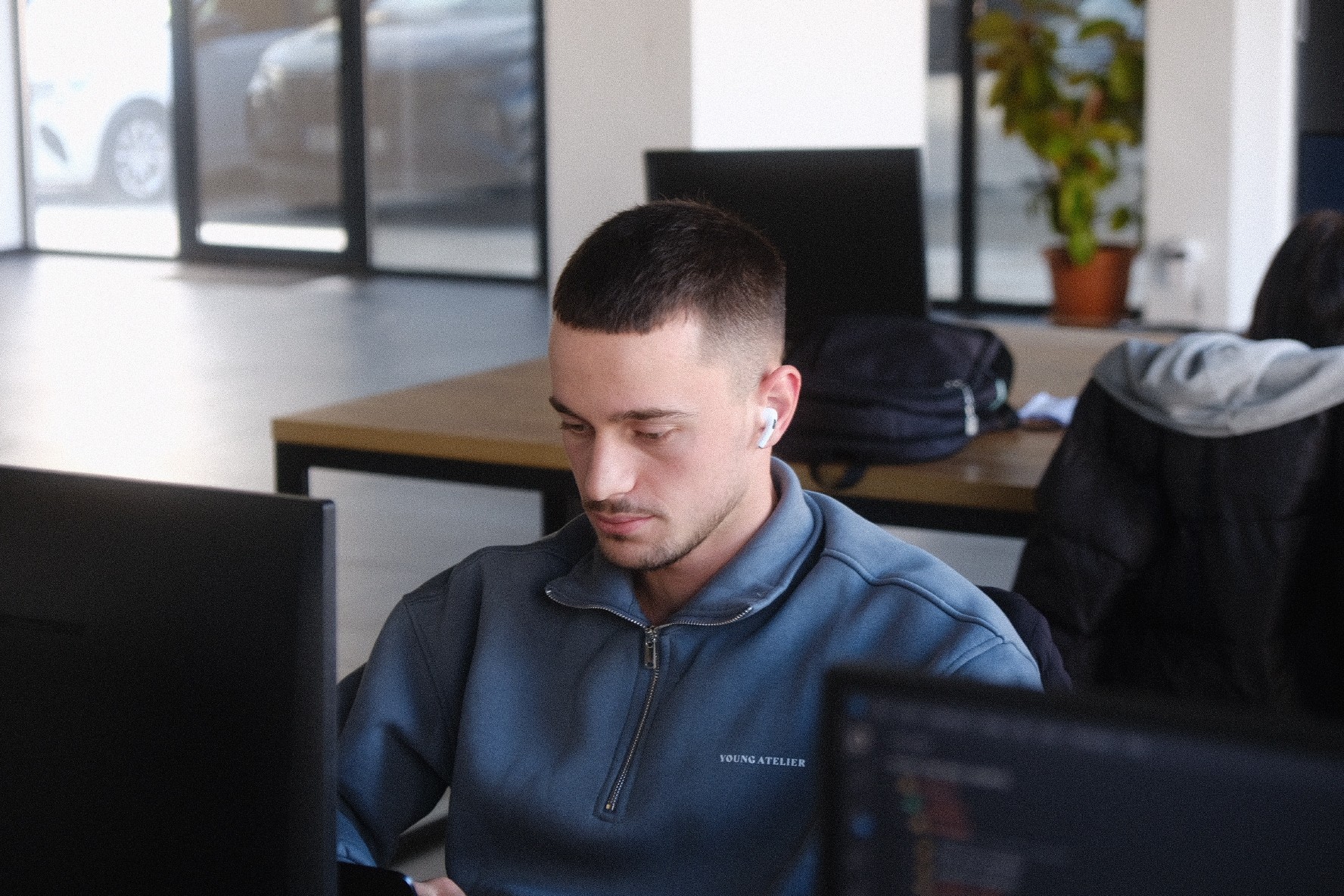 A silhouette of a person wearing sunglasses, with tousled hair, against a teal background.