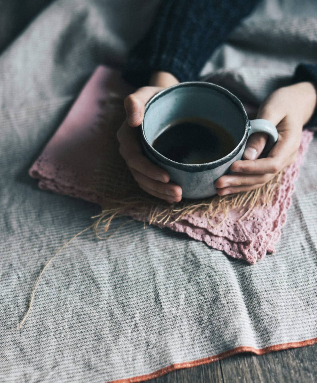 a womans hands holding a cup of tea