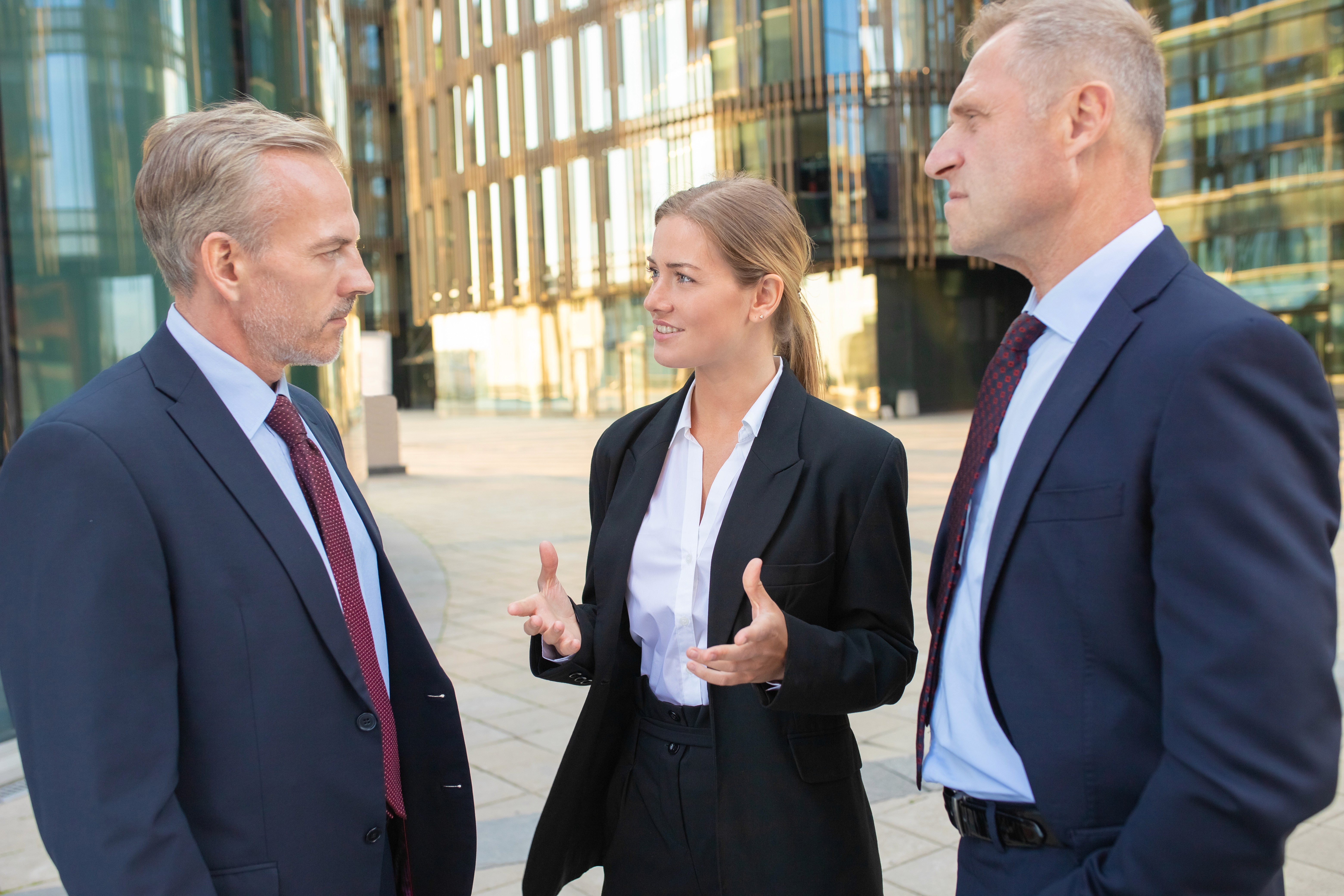 Businesswoman speaking with two executives outdoors