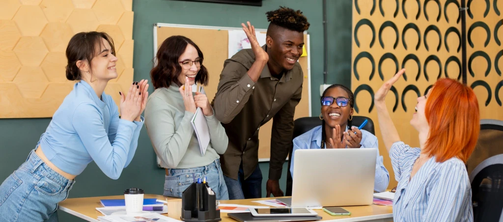 Team celebrating success around a laptop