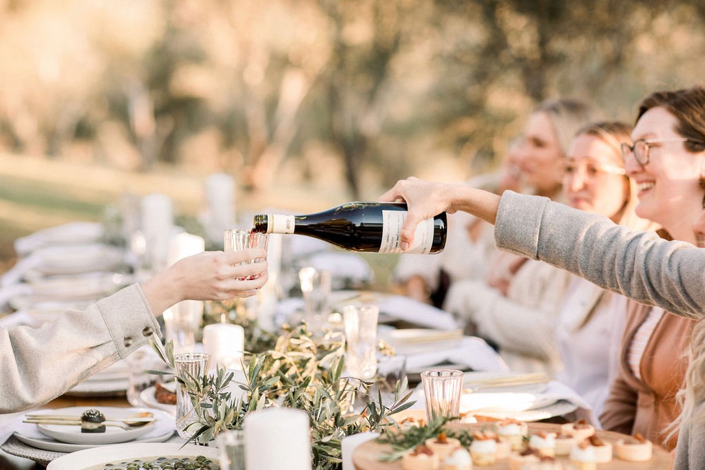 Guests pouring wine for each other over a Christmas Lunch table