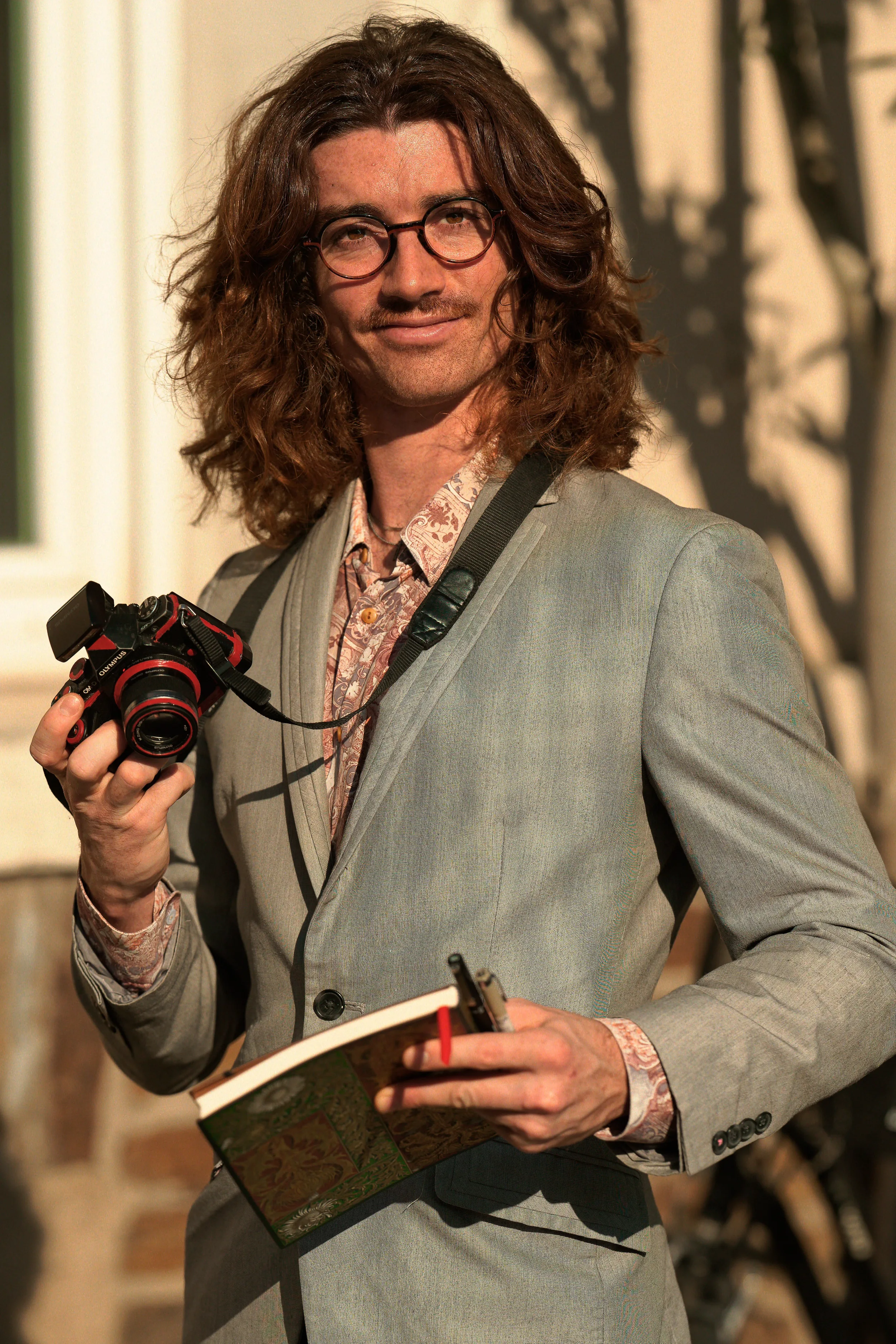 Martin Dedron, un professionnel de la création tenant son appareil photo et son calepin