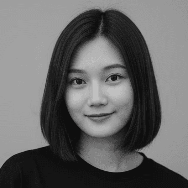Portrait of a woman with long, smooth hair swept to the side, in a dark t-shirt, on a plain background.