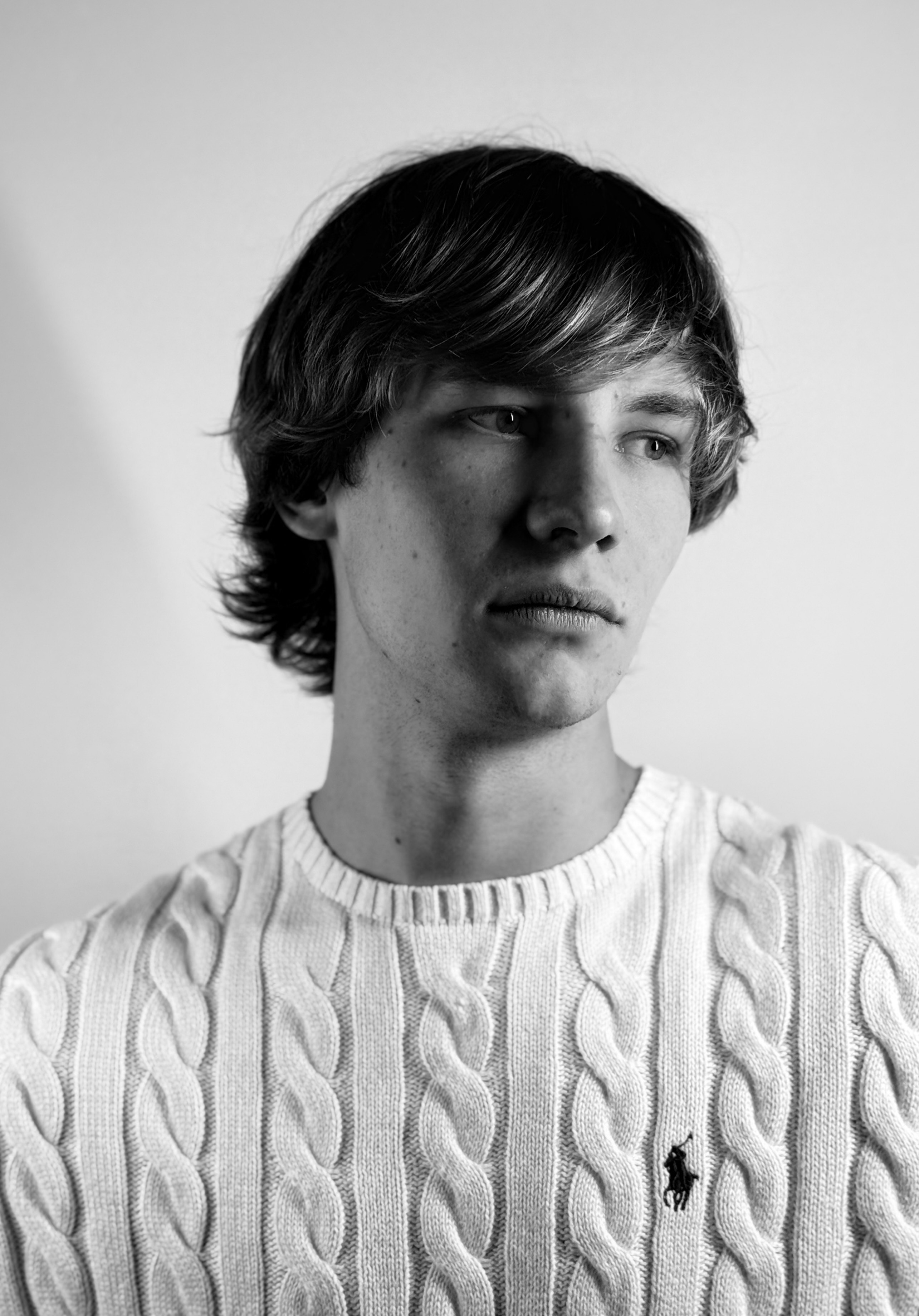 Portrait of a young man with short hair, wearing a dark t-shirt, against a plain background.