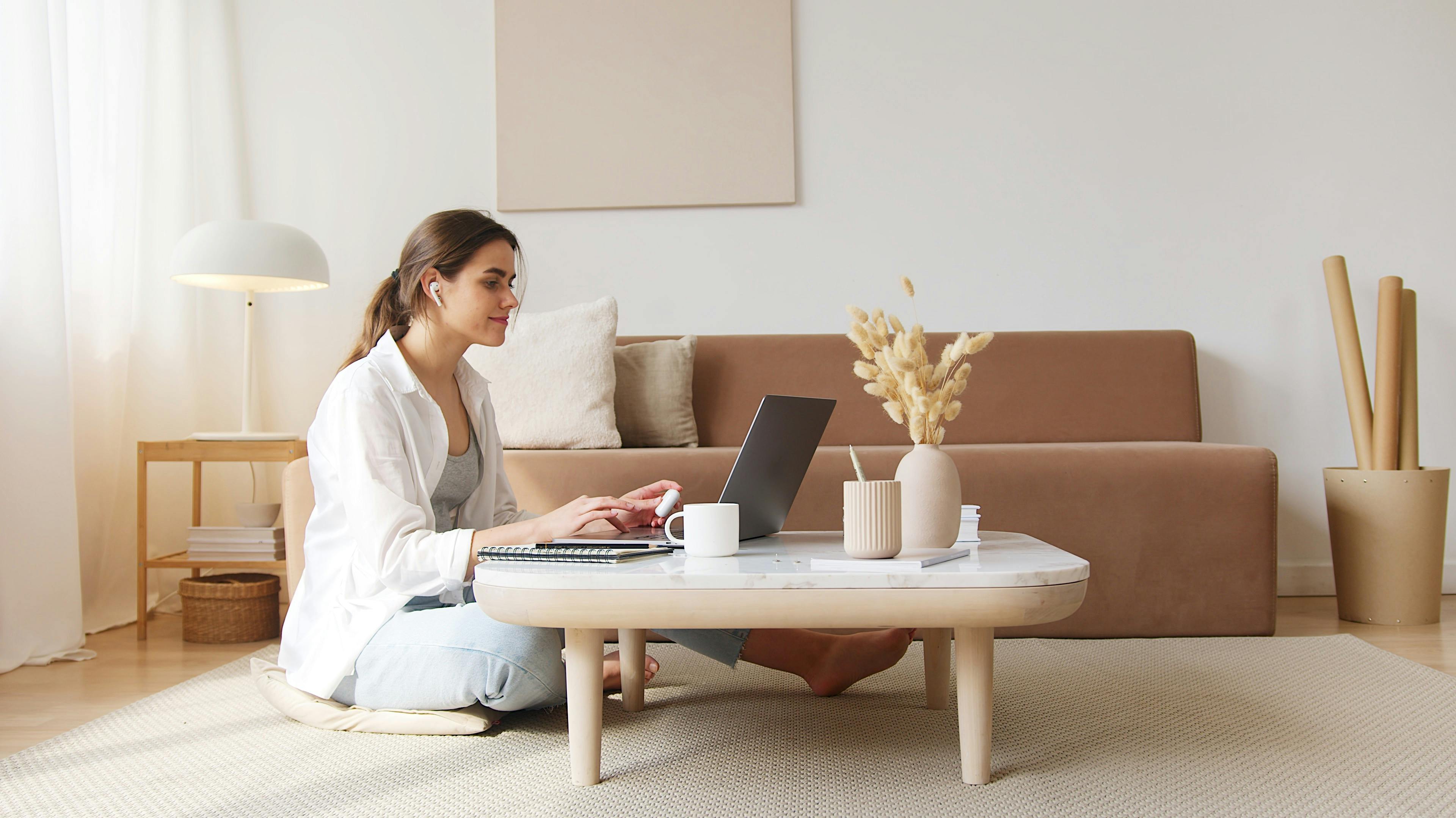 Donna che lavora da casa con il laptop in un ambiente ordinato e luminoso, rappresentazione di equilibrio tra lavoro e benessere grazie a percorsi di formazione online personalizzati.