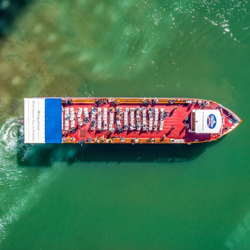 俯瞰一艘红色观光船，游客已就座，正巡游在碧绿的水域上。