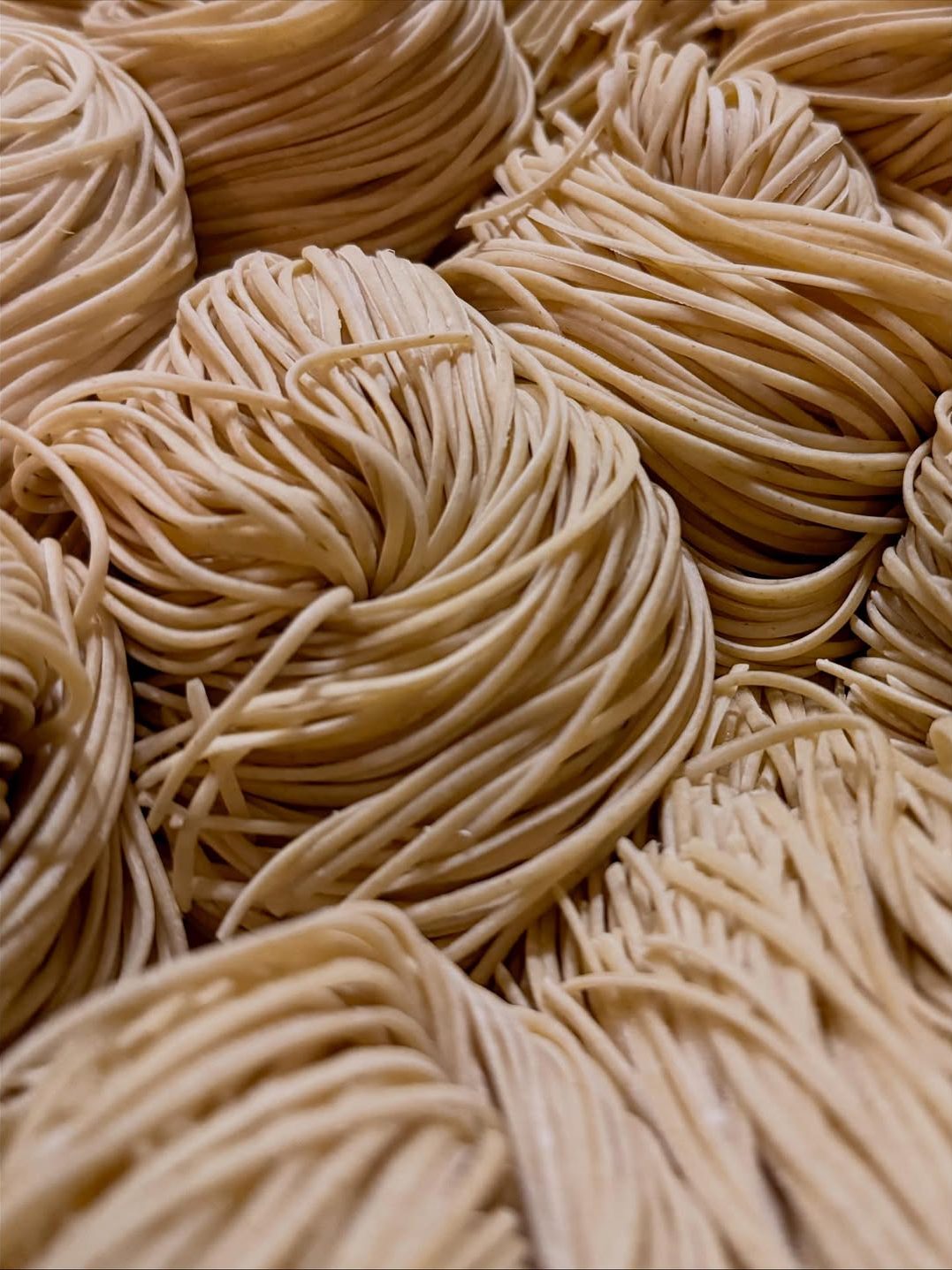 Close-up of intertwined strands of uncooked pasta, showcasing their texture and color.