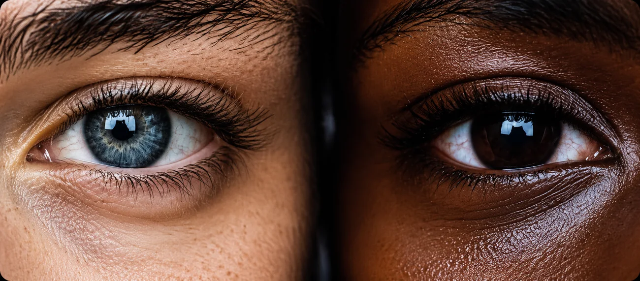 Close-up of two eyes side by side, one light blue and one dark brown, graded for color