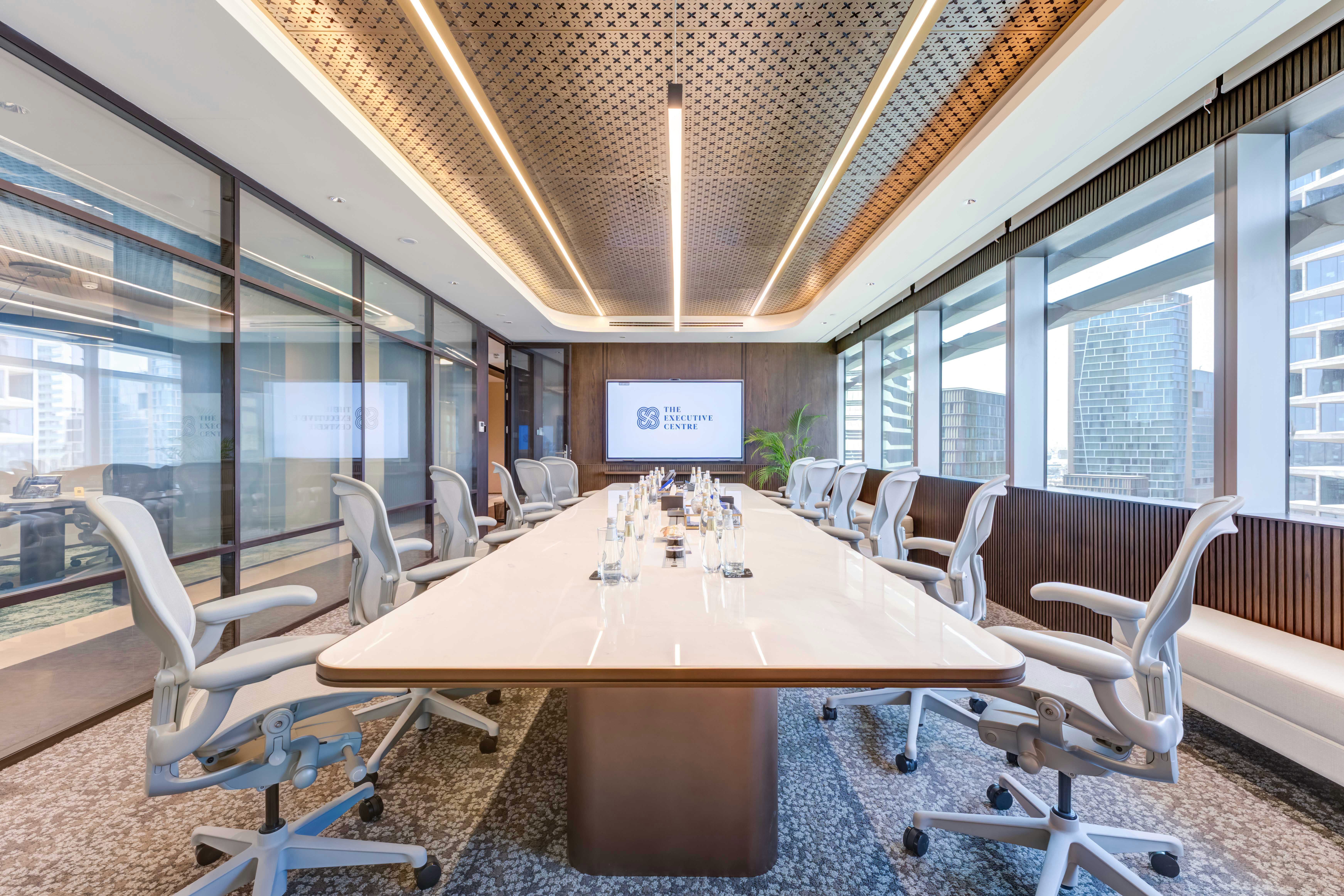 Large conference table in a well-lit space with a screen and city views.