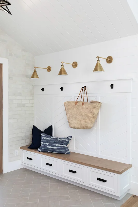 White entryway bench, brass wall hooks, navy striped cushion in North Tustin Remodel & Addition. Photo by Molly Rose.