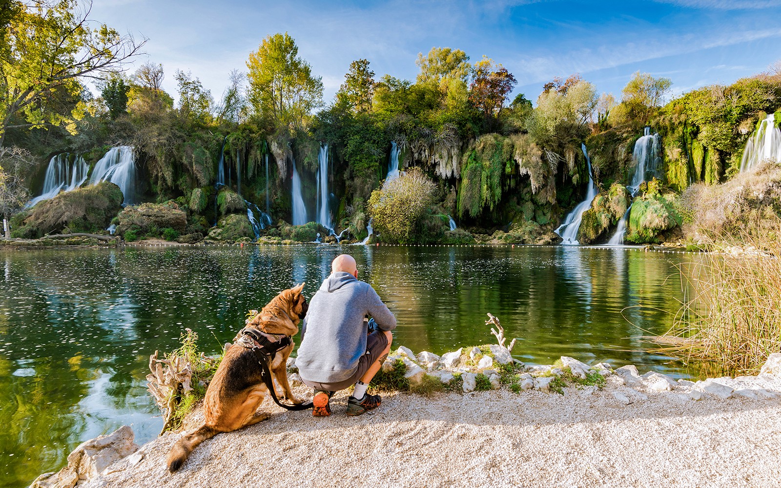 Man with dog by Kravica waterfall in Bosnia.