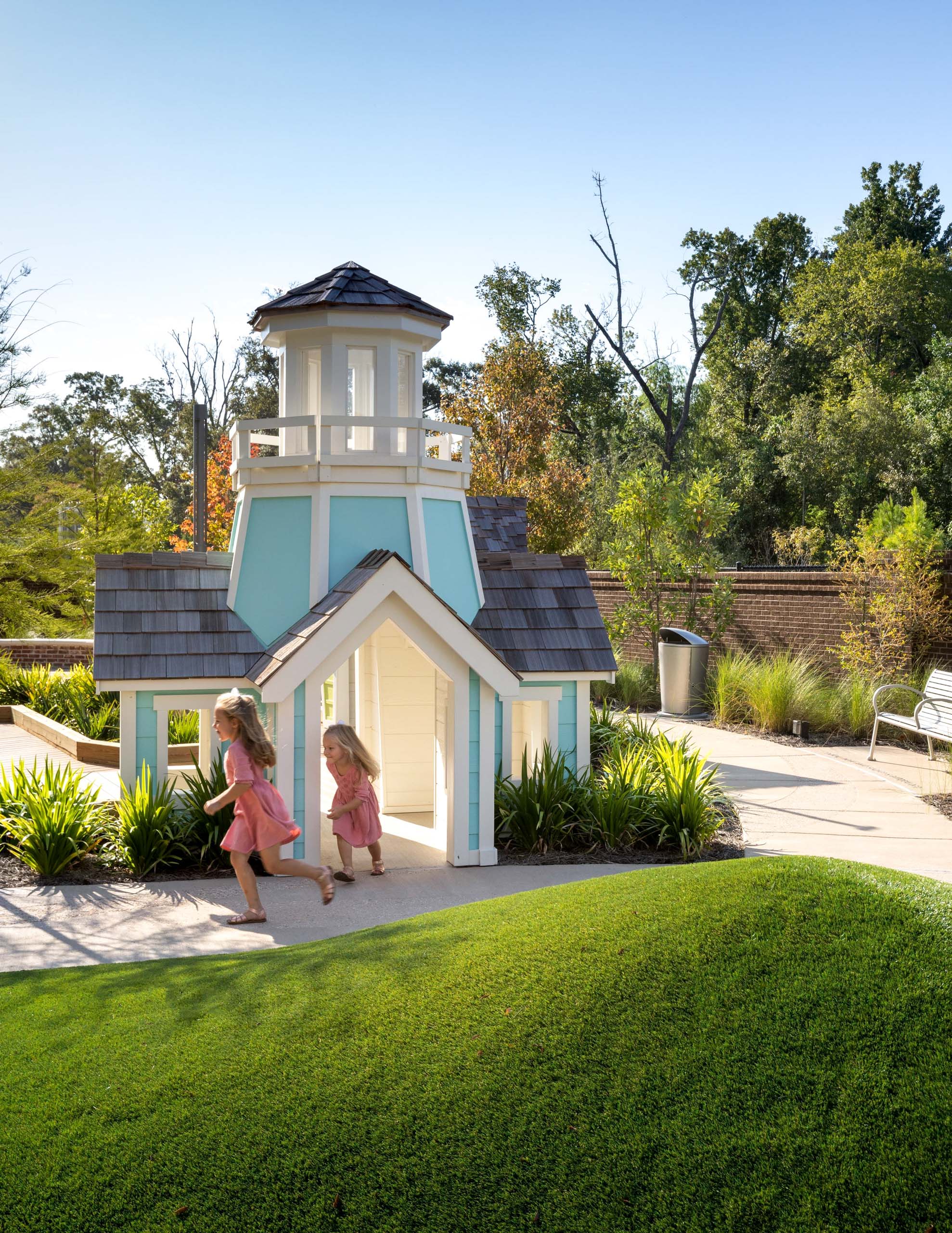 Two girls run past a playhouse.