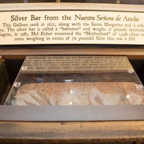 Display case containing a silver bar with an informational plaque about the Nuestra Señora de Atocha shipwreck.