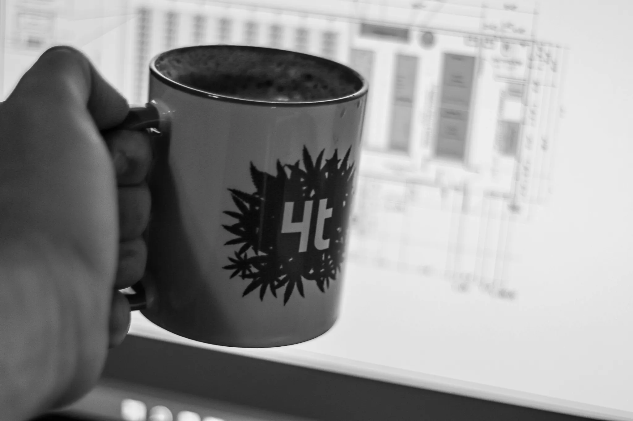 4trees mug cheers, overlooking a facility plan on the computer